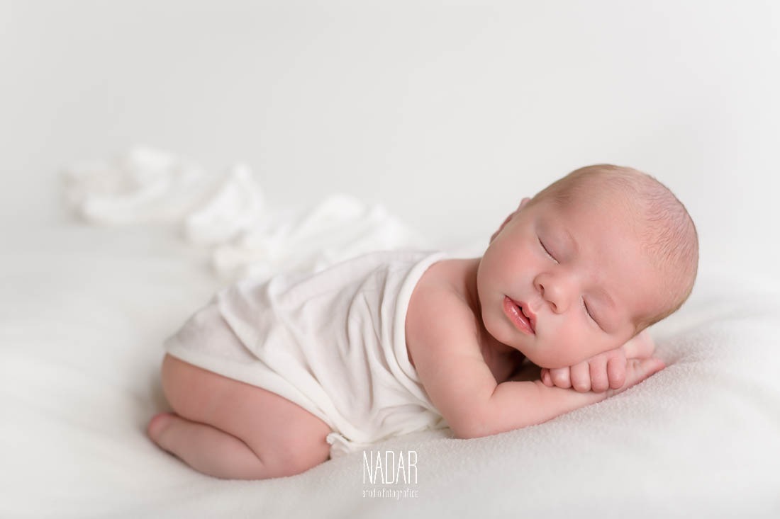 neonato che dorme su coperta bianca durante servizio fotografico