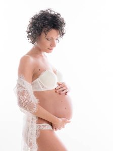 Donna in intimo durante servizio fotografico di gravidanza