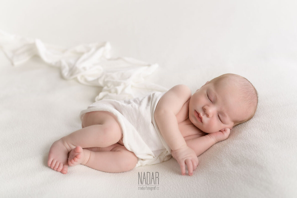 Neonato che dorme su copertina bianca , durante servizio fotografico