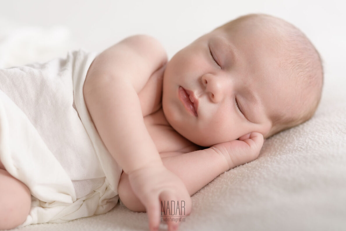 Neonato che dorme su copertina bianca , durante servizio fotografico