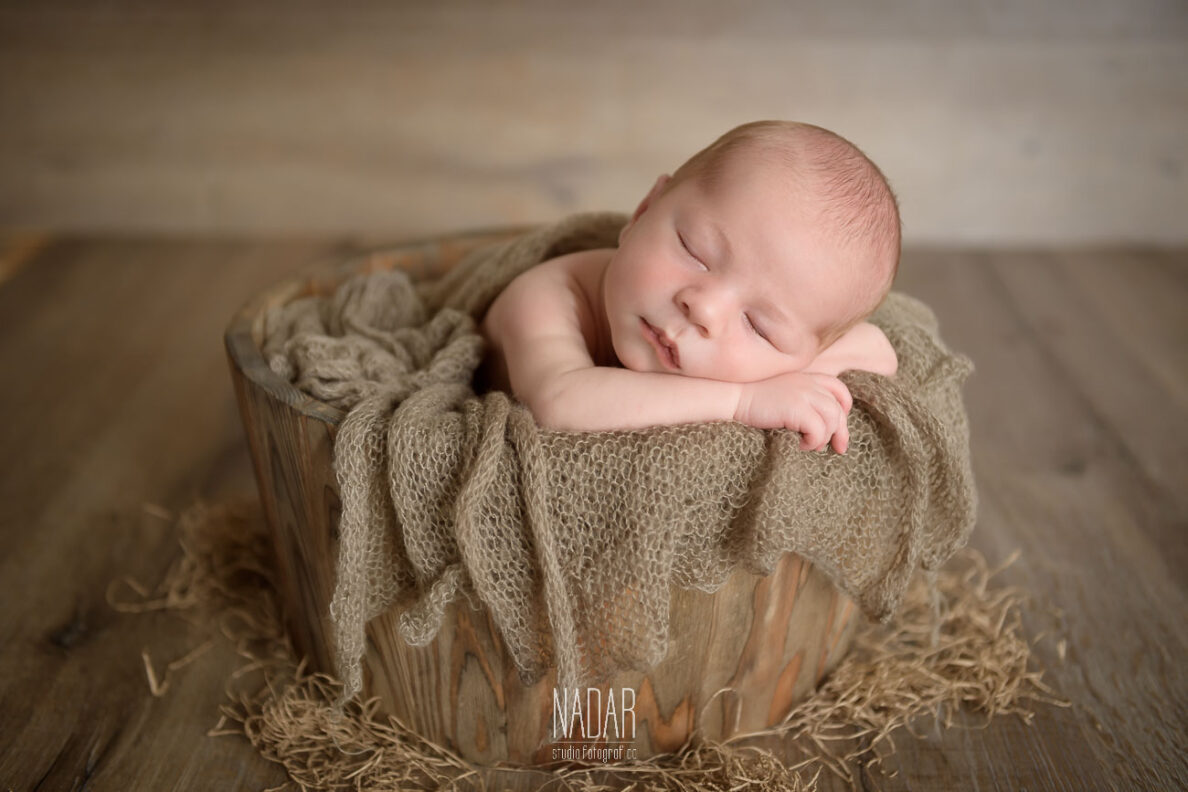 neonato dentro un mastello in legno , durante un servizio fotografico
