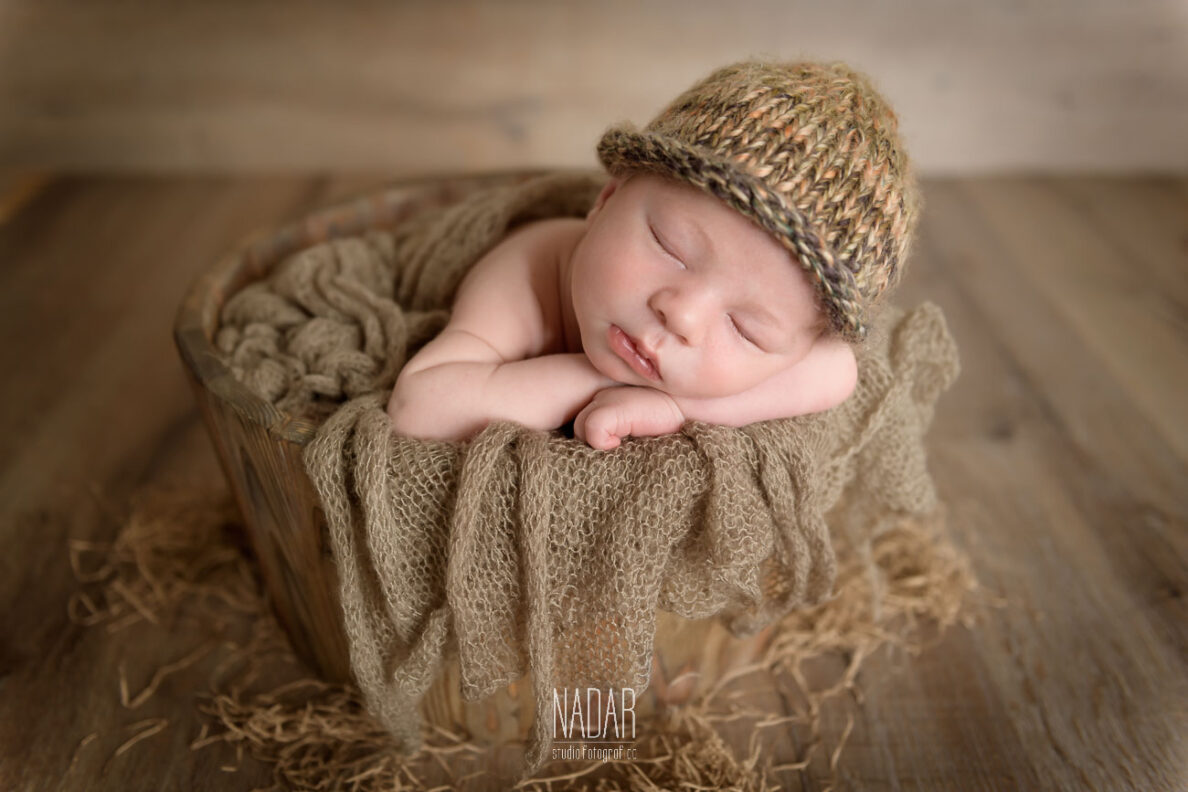 servizio fotografico con neonato dentro un cestino in legno.