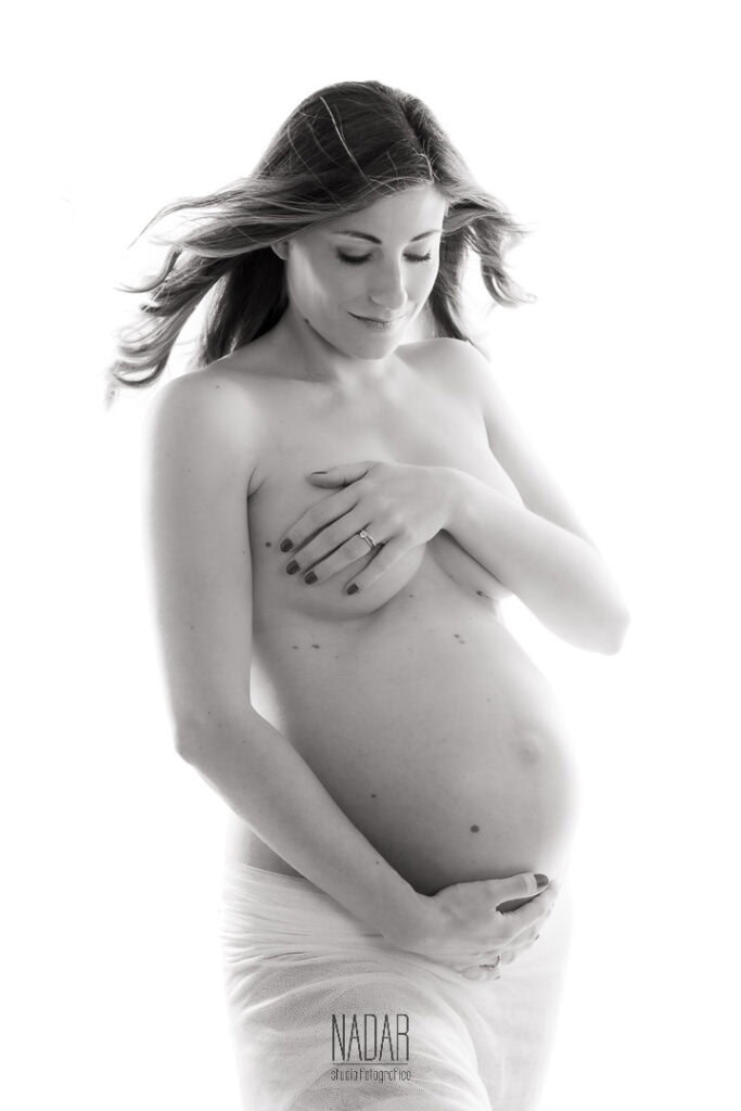 Donna incinta che si copre il seno con le mani, in stile artistico e minimalista.