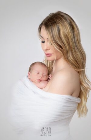 neonato che dorme tra le braccia della mamma , avvolto nel tulle