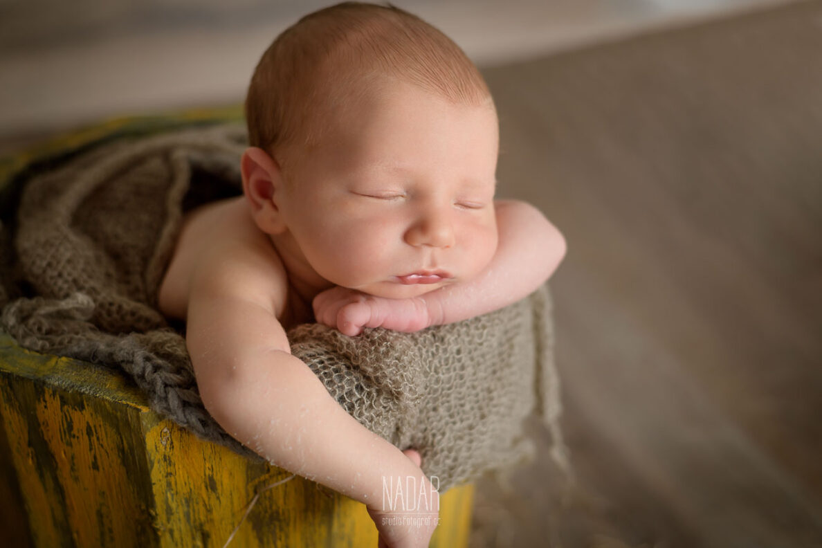 neonato che dorme dentro mastello durante servizio fotografico